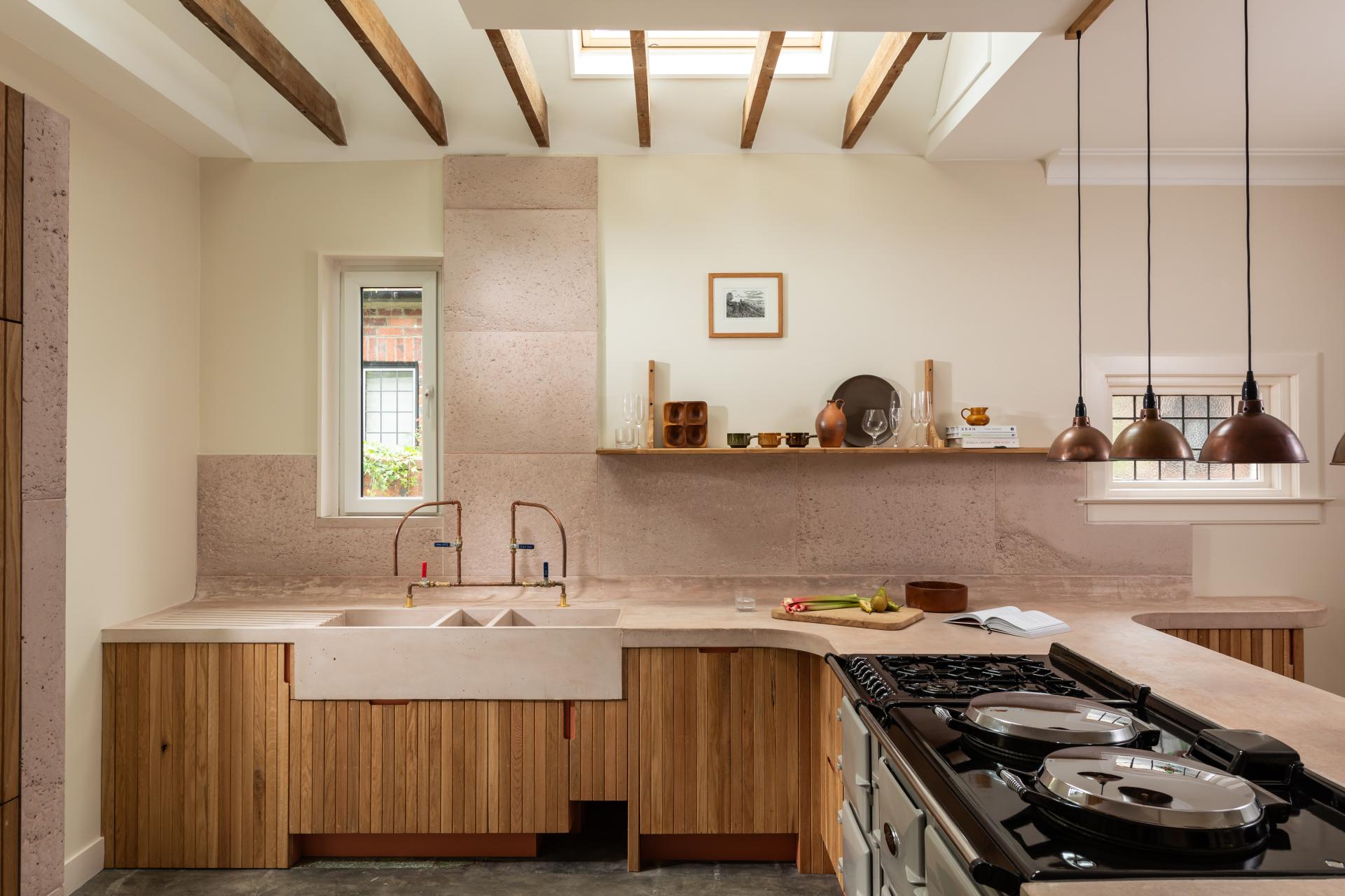 Elegant kitchen featuring poured pink concrete and Scottish Oak cabinetry, accented by artistic lighting and rustic decor.
