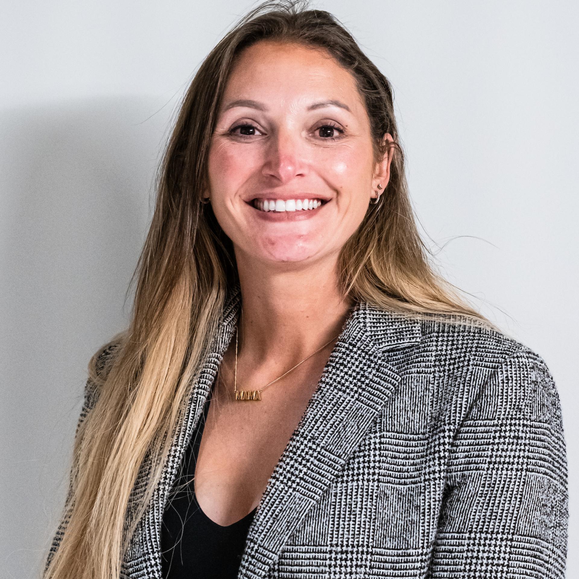Smiling woman in a blazer, representing the growing importance of co-living in Manchester's property sector.