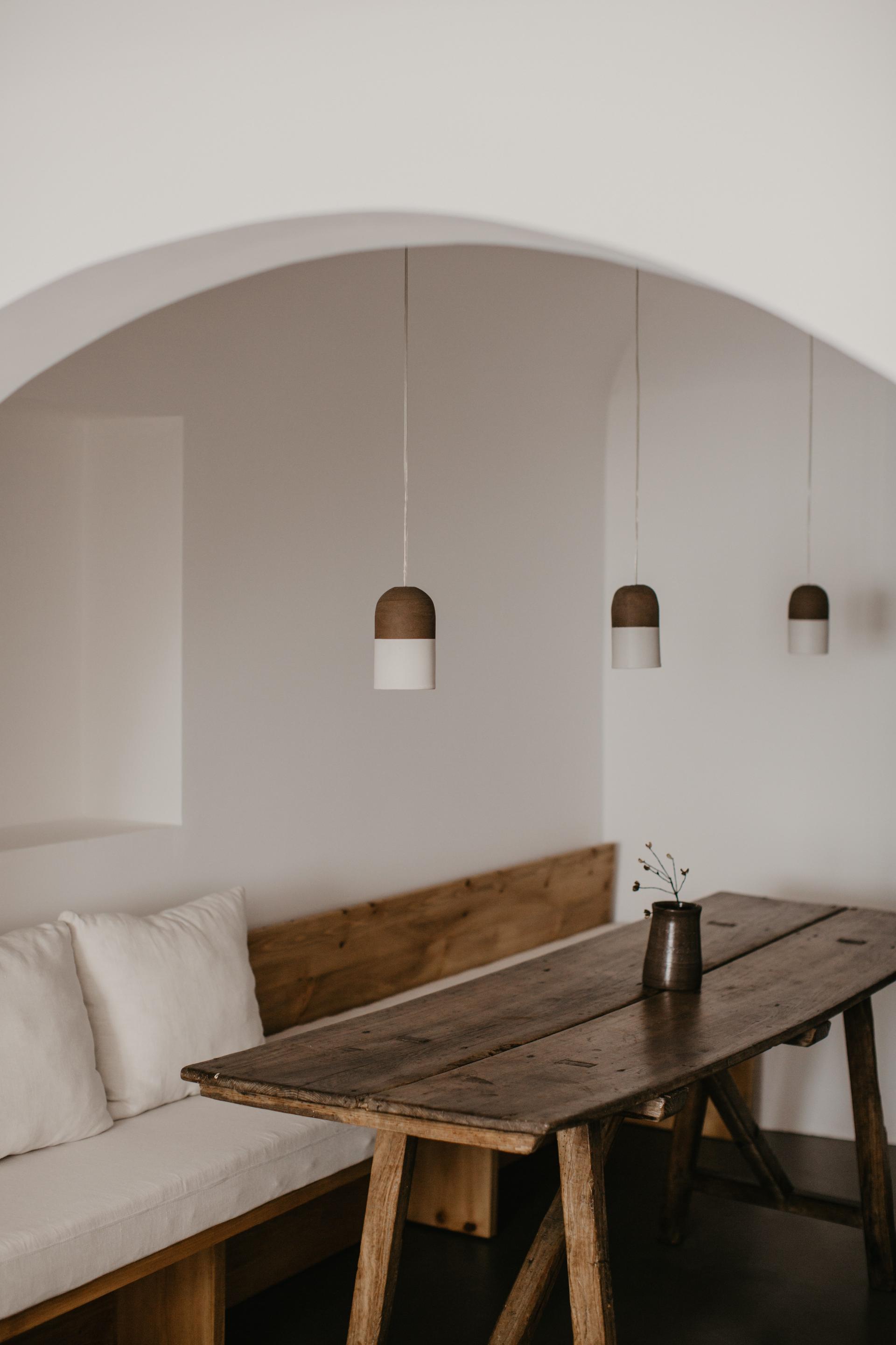 Natural wood furniture and minimalist pendant lights create a harmonious interior, showcasing Quadrodesign's Source collection in a restored space.