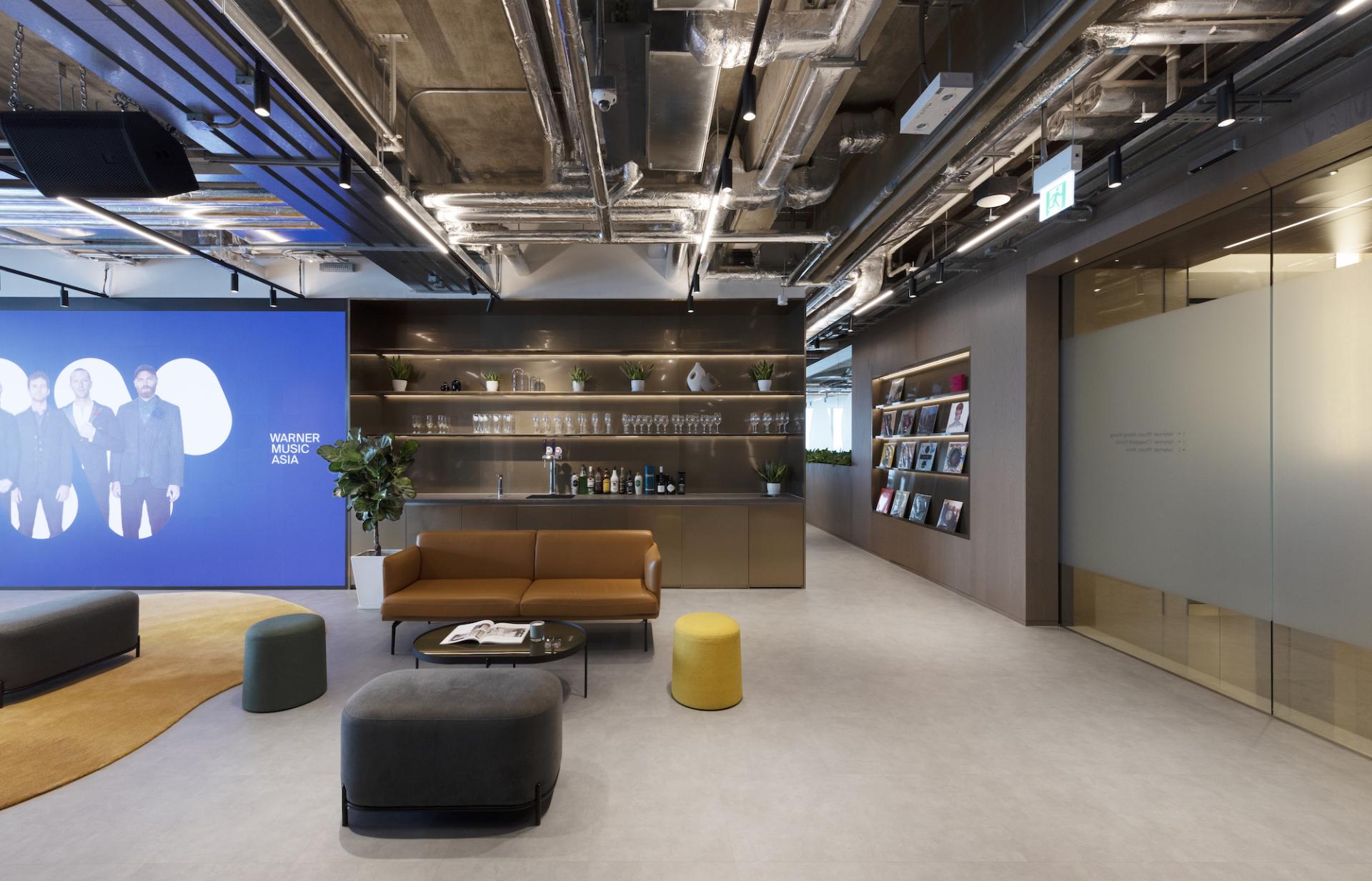 Modern office interior of Warner Music Hong Kong featuring a lounge area, artwork, and stylish design elements.
