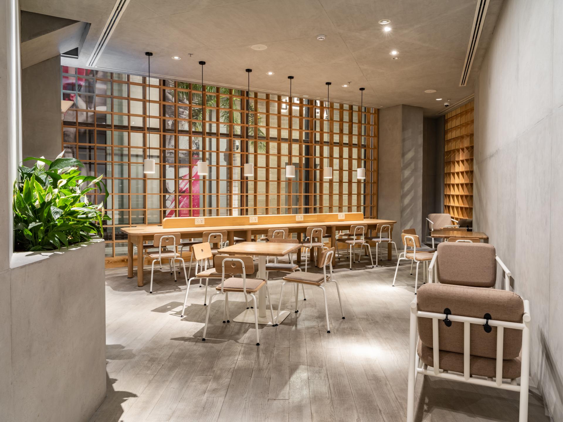 Modern coffee shop interior featuring a Japandi aesthetic with wooden furniture, greenery, and inviting ambiance.