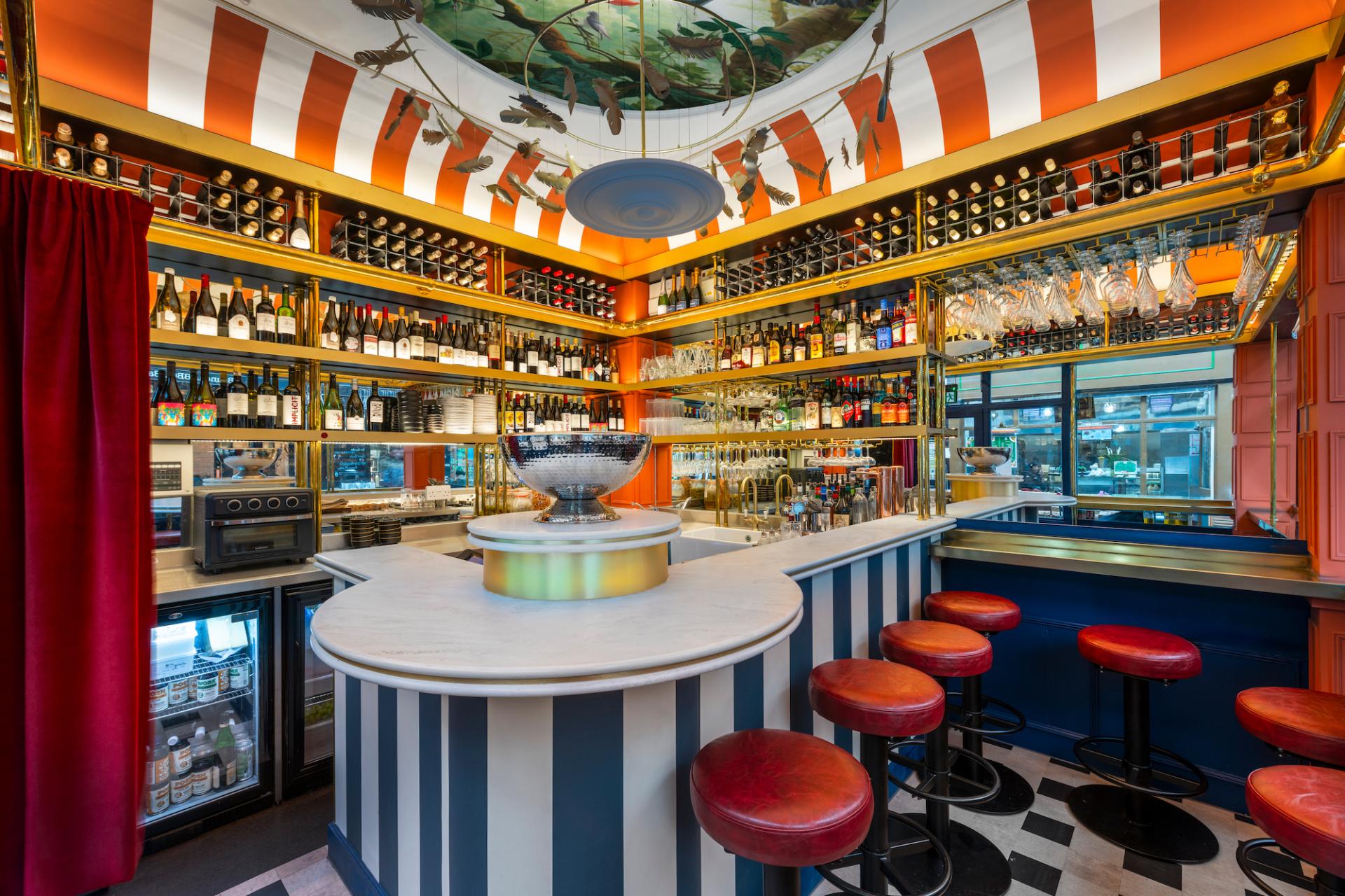 Vibrant bar interior in Brixton, featuring a marble countertop, colorful shelves of bottles, and stylish seating.