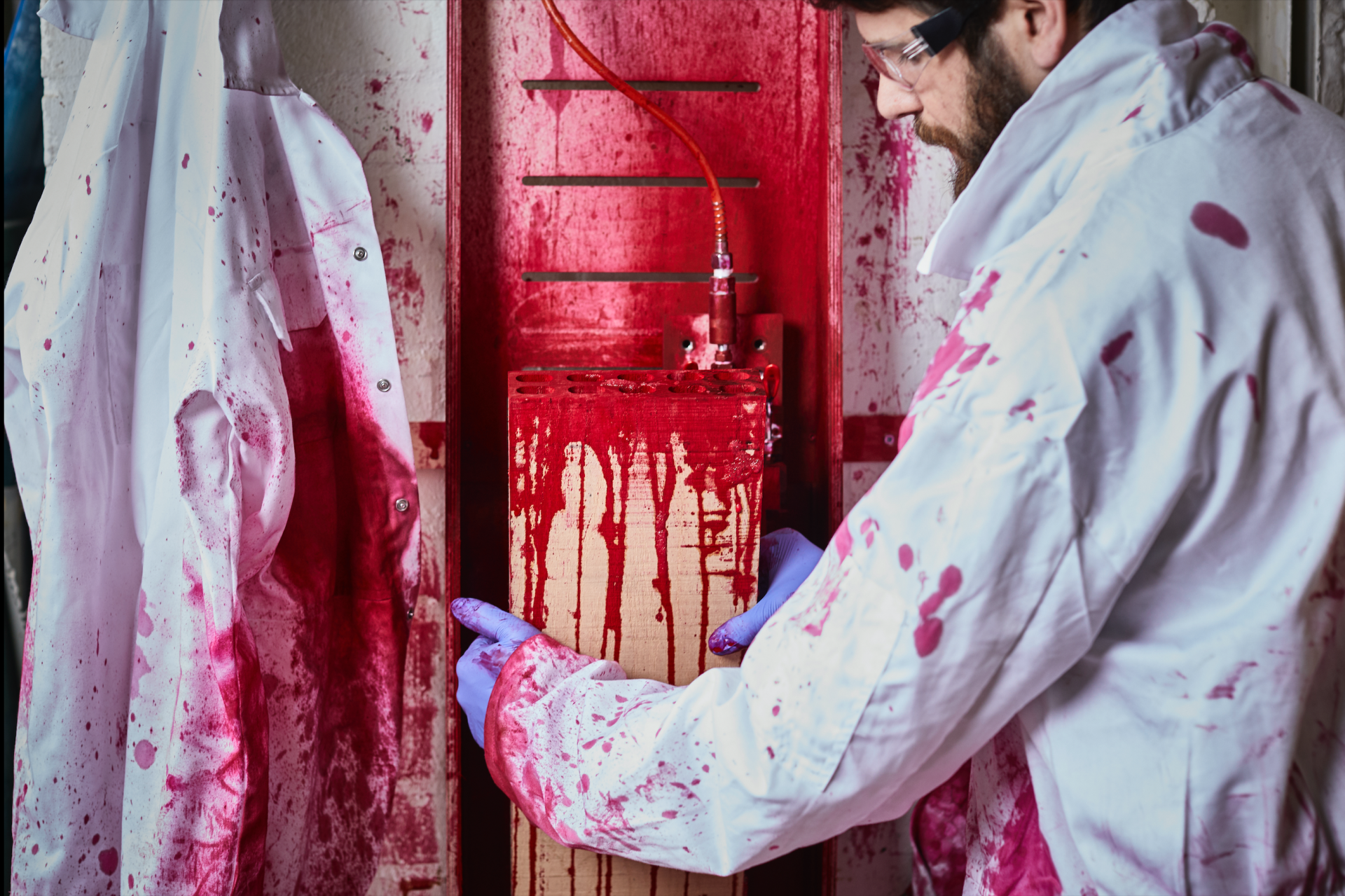 Craftsman applying red dye to a red oak panel for a Blushing Bar design at Milan Design Week.