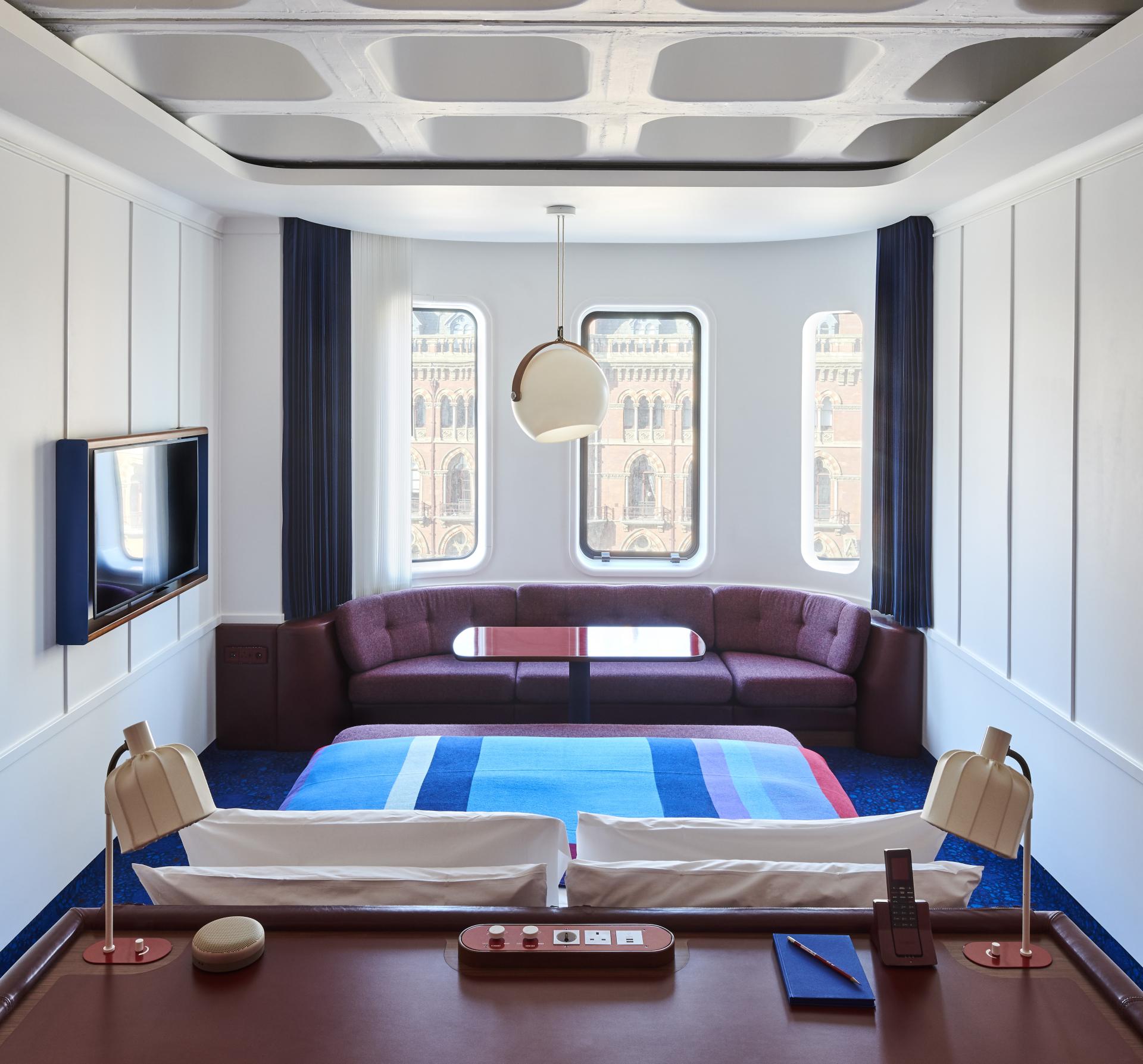 Stylish hotel room at The Standard, London, featuring modern decor, large windows, and views of St Pancras station.