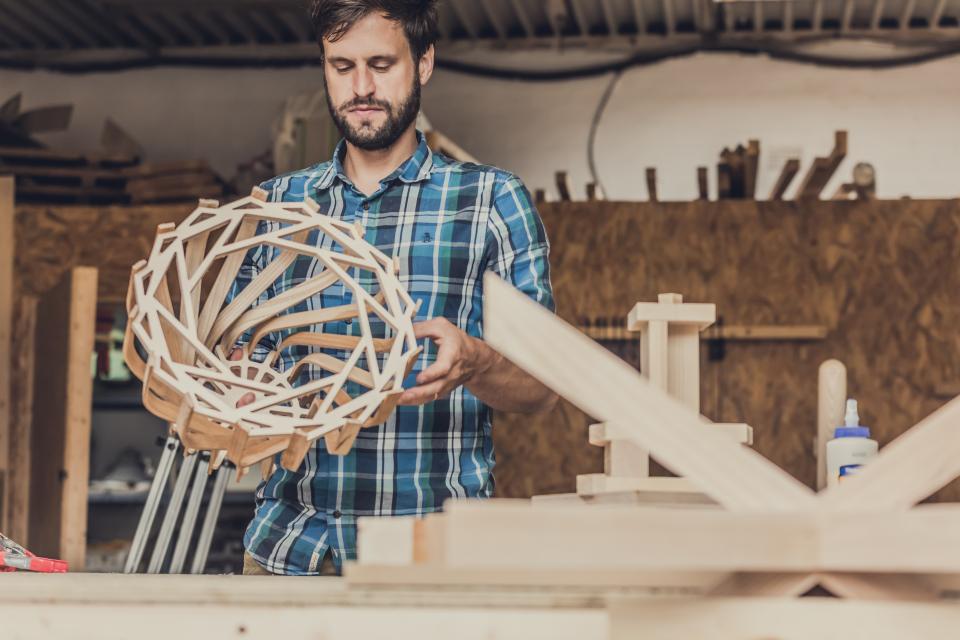 Craftsman shaping a unique, hand-crafted lampshade inspired by art deco design in a workshop setting.