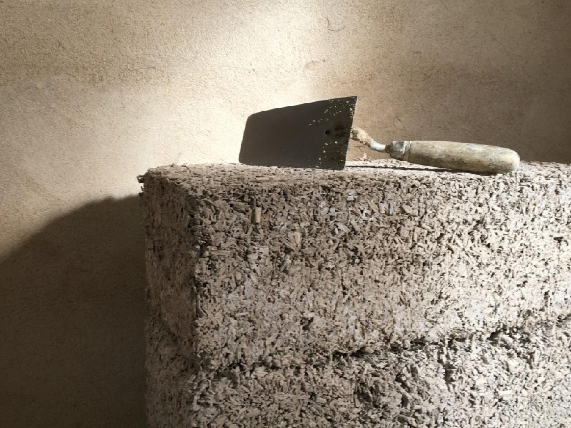 Hand trowel resting on a textured block made from biomaterial, showcasing sustainable construction methods for low carbon buildings.