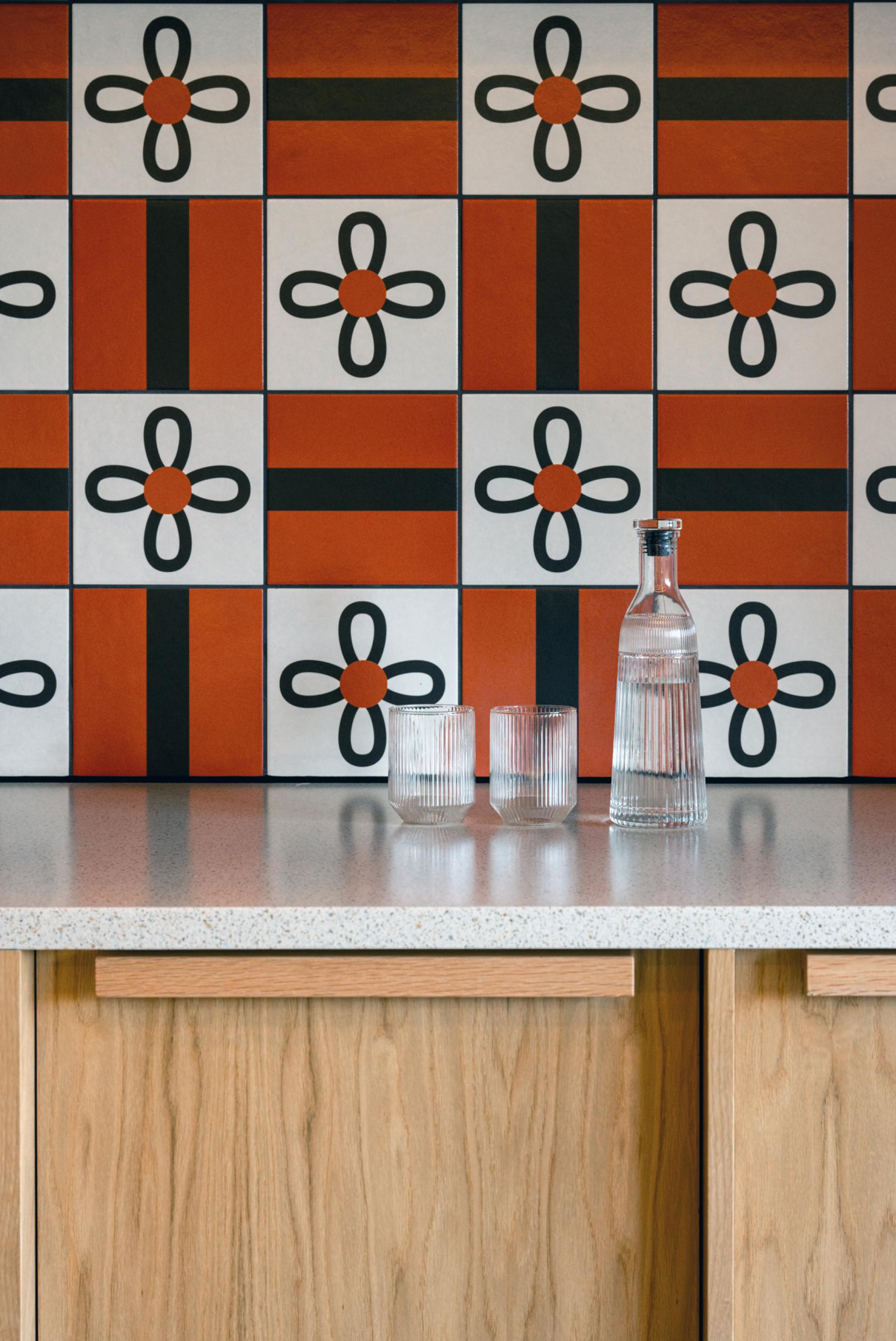 Colorful patterned wall with a minimalist countertop featuring a glass water bottle and two glasses, reflecting Scottish design heritage.