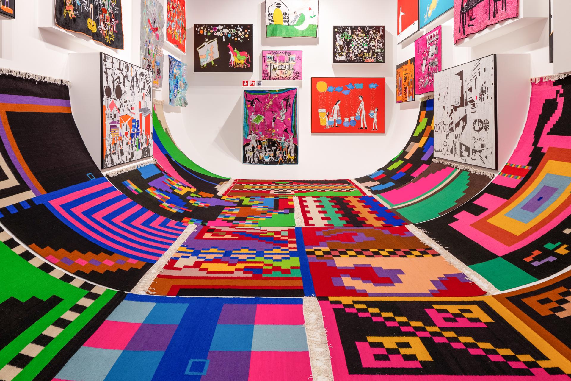 Colorful woven rugs create a vibrant installation, showcasing contemporary craft art within the Harewood Biennial 2024.