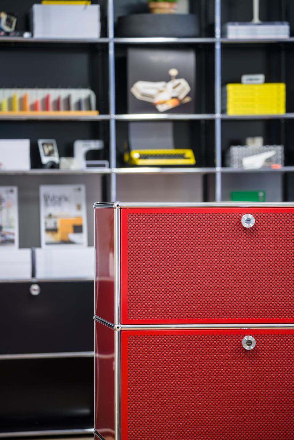 Red modular furniture from USM showcased in a modern showroom setting with various design accessories in the background.