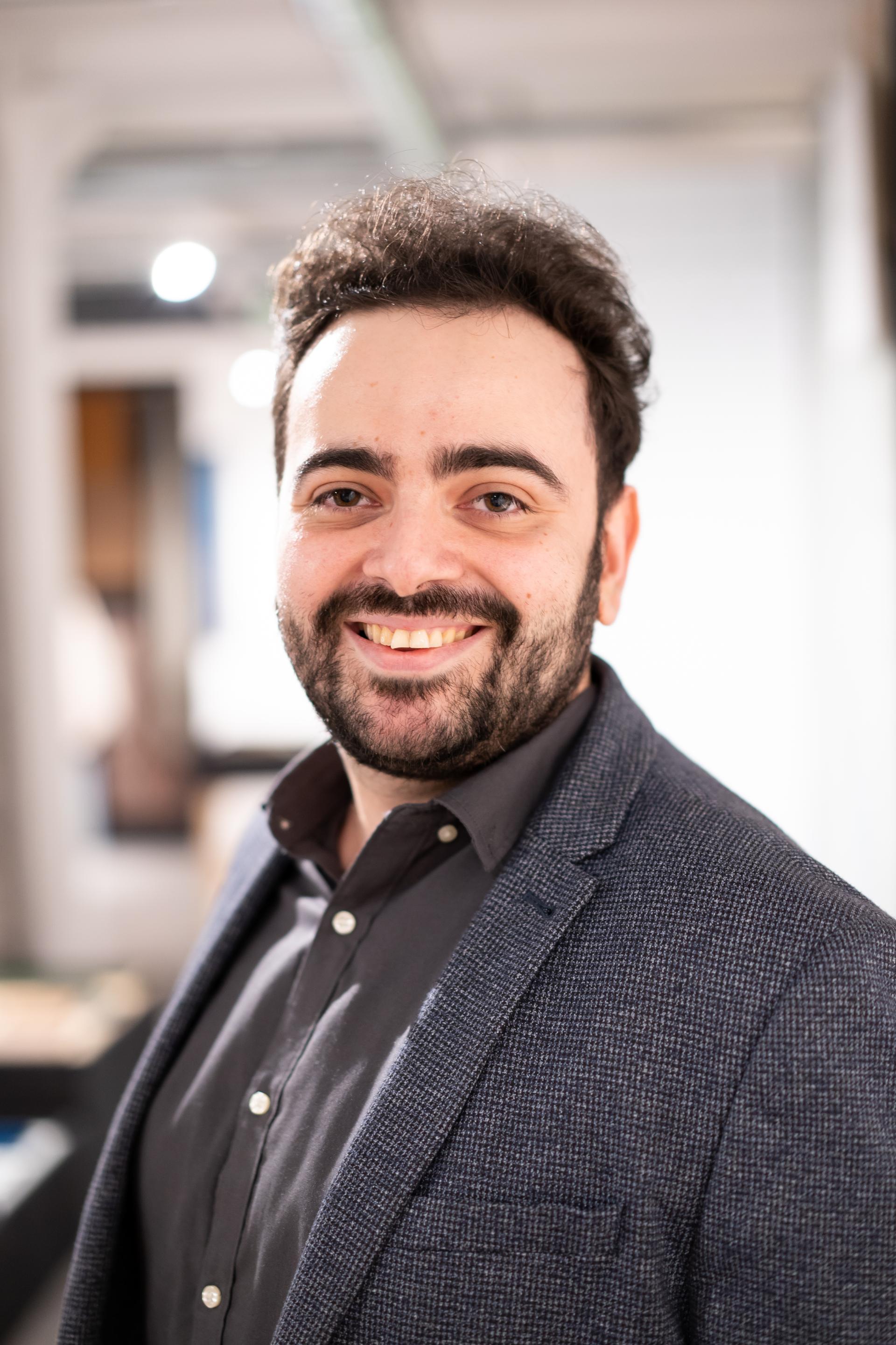 Smiling man in a blazer, representing personal connections in sustainability discussions at a seminar.