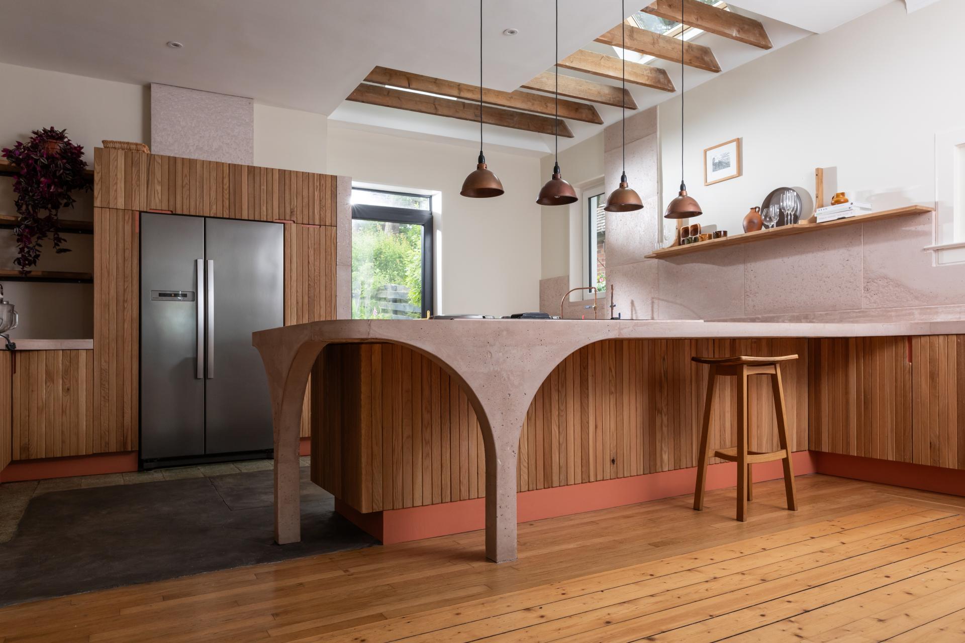 Stylish kitchen featuring poured pink concrete countertops and Scottish Oak cabinetry with curved design elements.