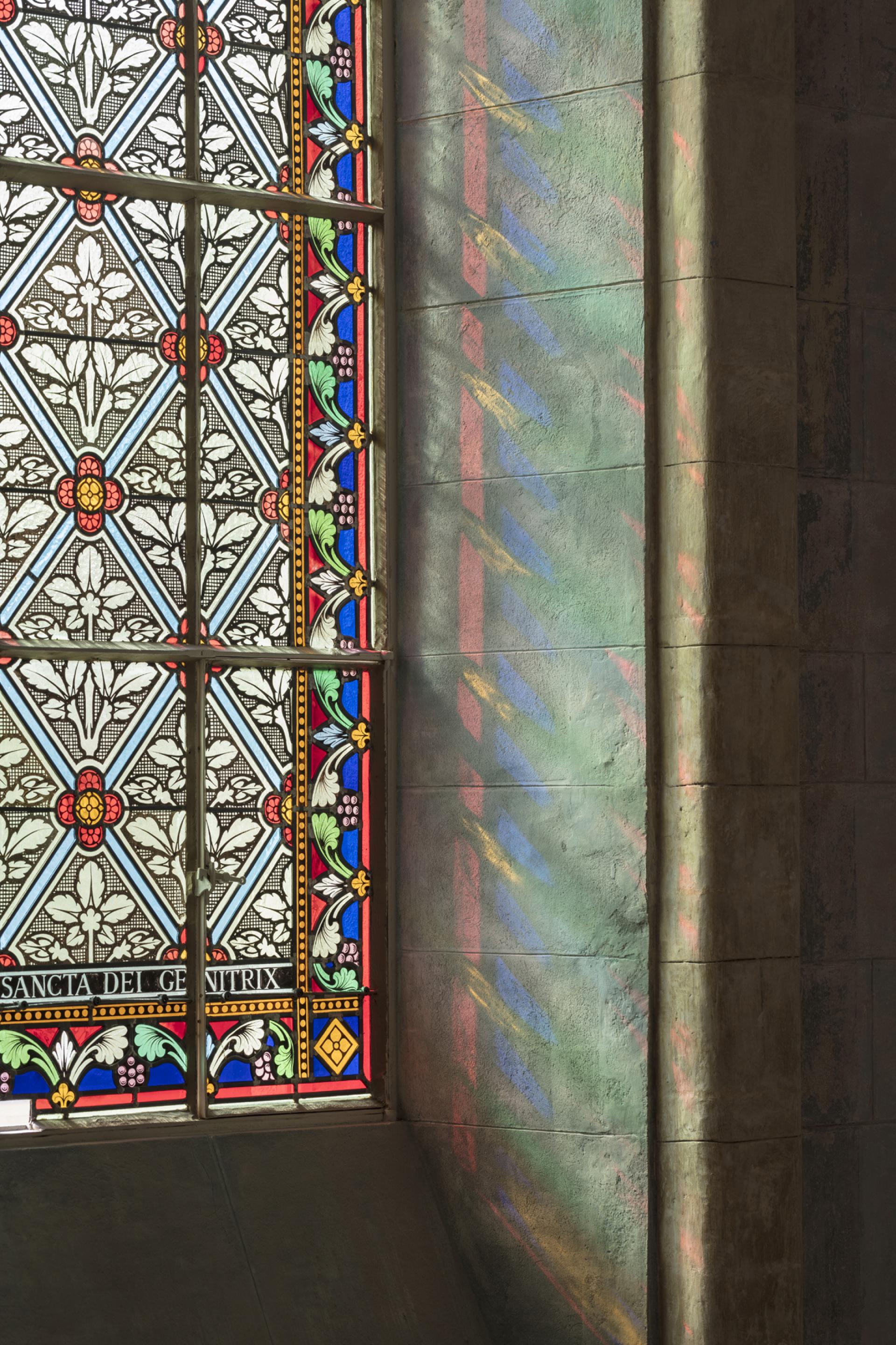 Stained glass window vibrant with intricate floral patterns, casting colorful reflections on the stone wall of The Jaffa.