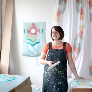 Scottish visual artist Jenny Steele in her studio, surrounded by colorful textile designs and artwork inspired by seaside towns.