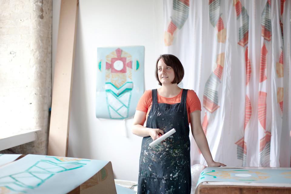Scottish visual artist Jenny Steele in her studio, surrounded by colorful textile designs and artwork inspired by seaside towns.