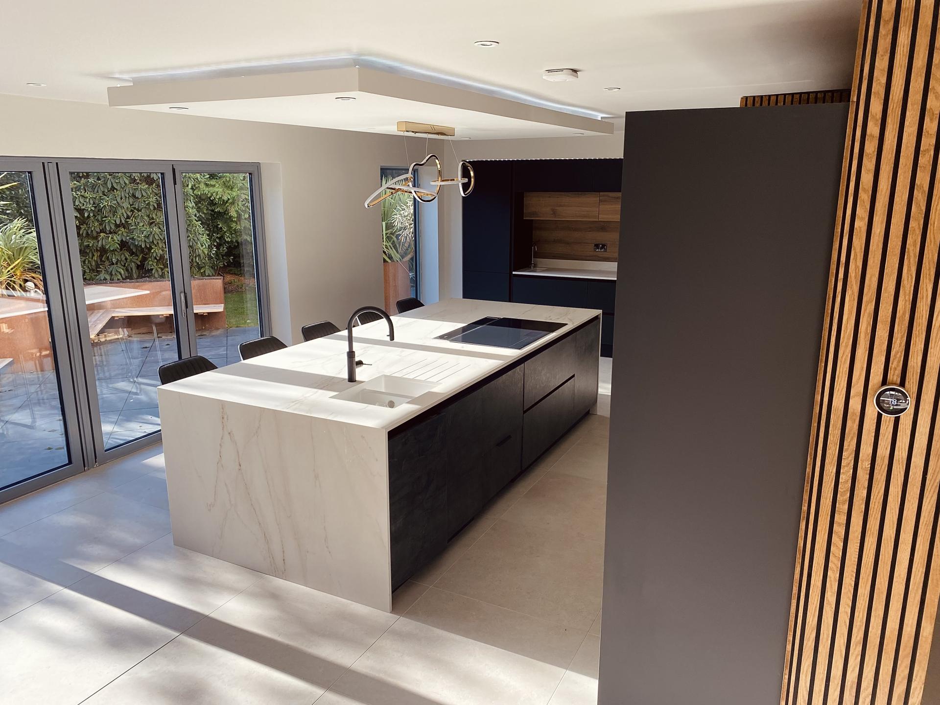 Contemporary kitchen design featuring a large marble island, sleek cabinetry, and abundant natural light from large windows.