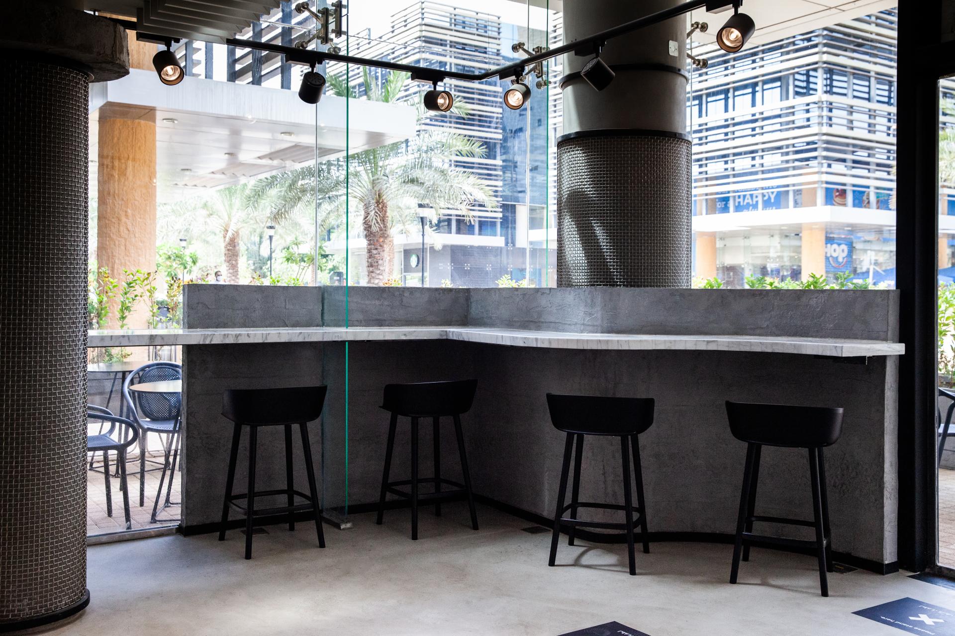Modern café interior featuring a sleek marble countertop and high stools, designed for the new Chunk locations in Riyadh.