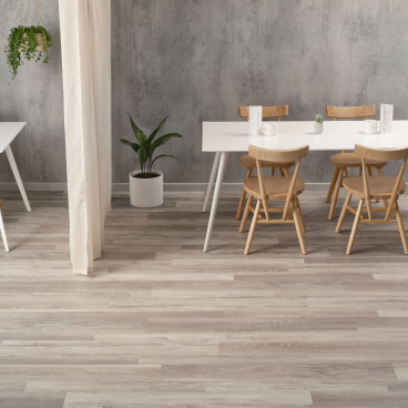 Modern dining area featuring natural decor, light wood chairs, white tables, and greenery, embodying biophilic design principles.