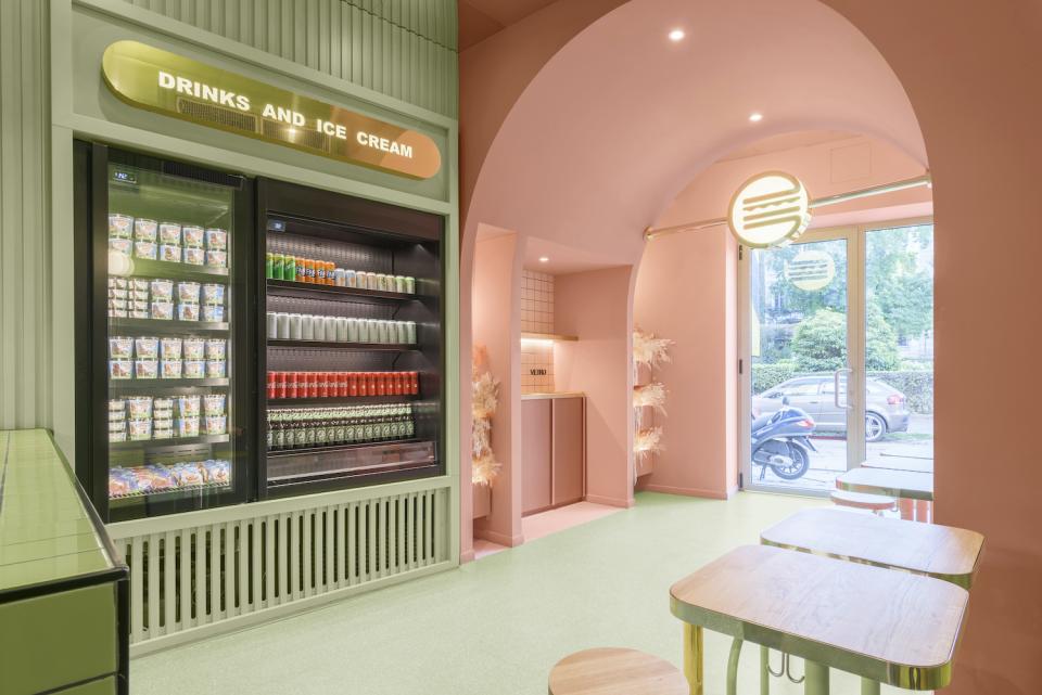 Colorful interior of Masquespacio's Bun in Milan, featuring a drinks display and welcoming seating area for customers.