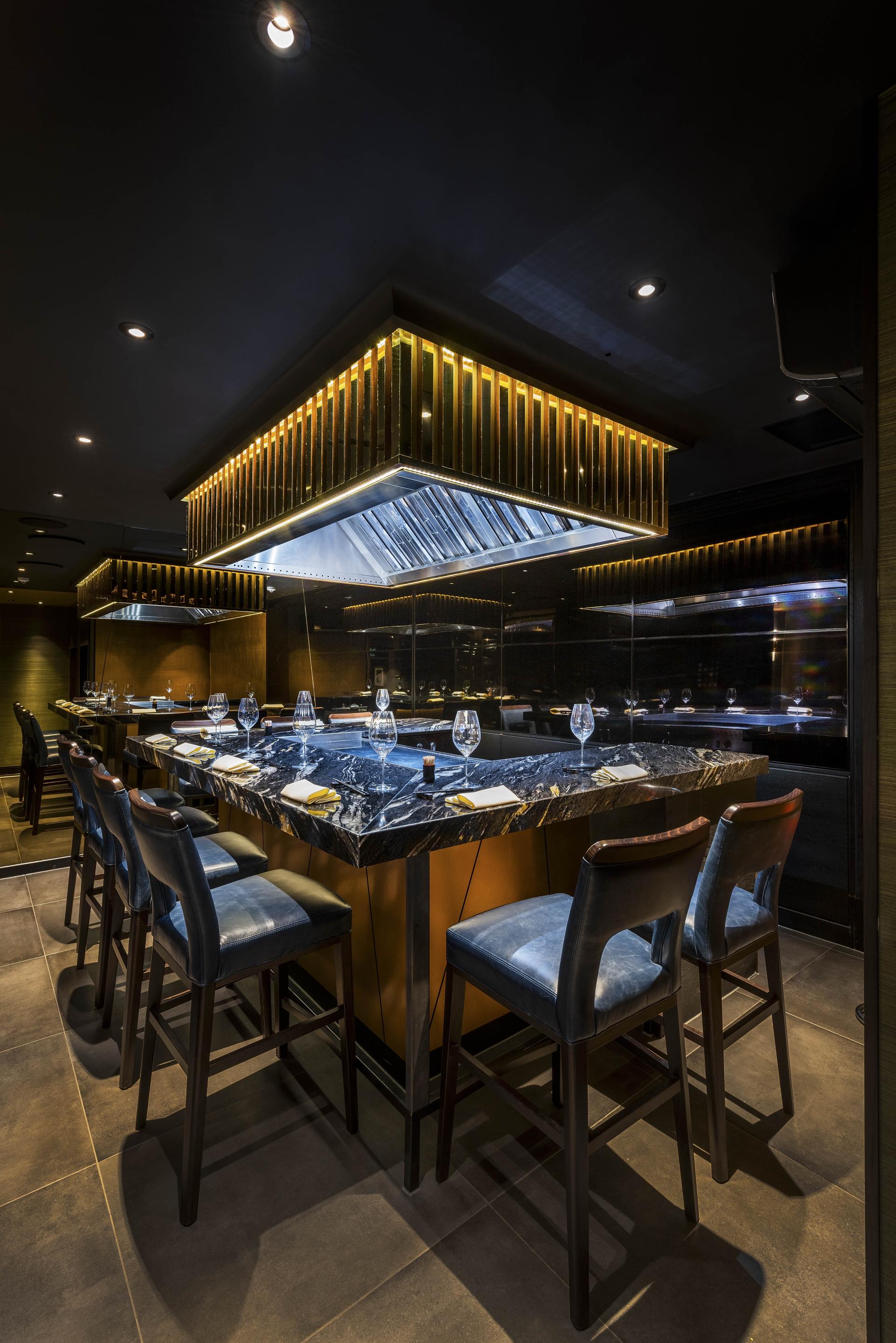 Elegant dining area featuring a luxurious marble countertop and stylish blue bar stools at The Colony Club.
