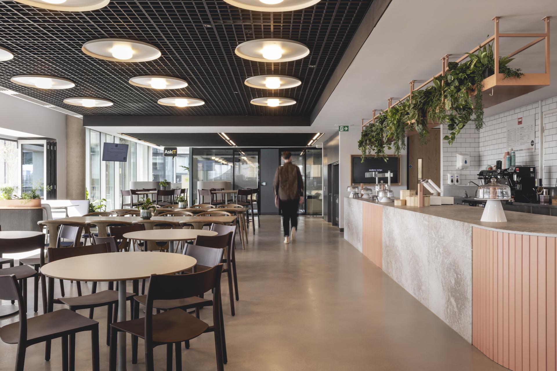 Modern workspace at AstraZeneca UK featuring a café area with stylish seating and a vibrant design by Ekho Studio.