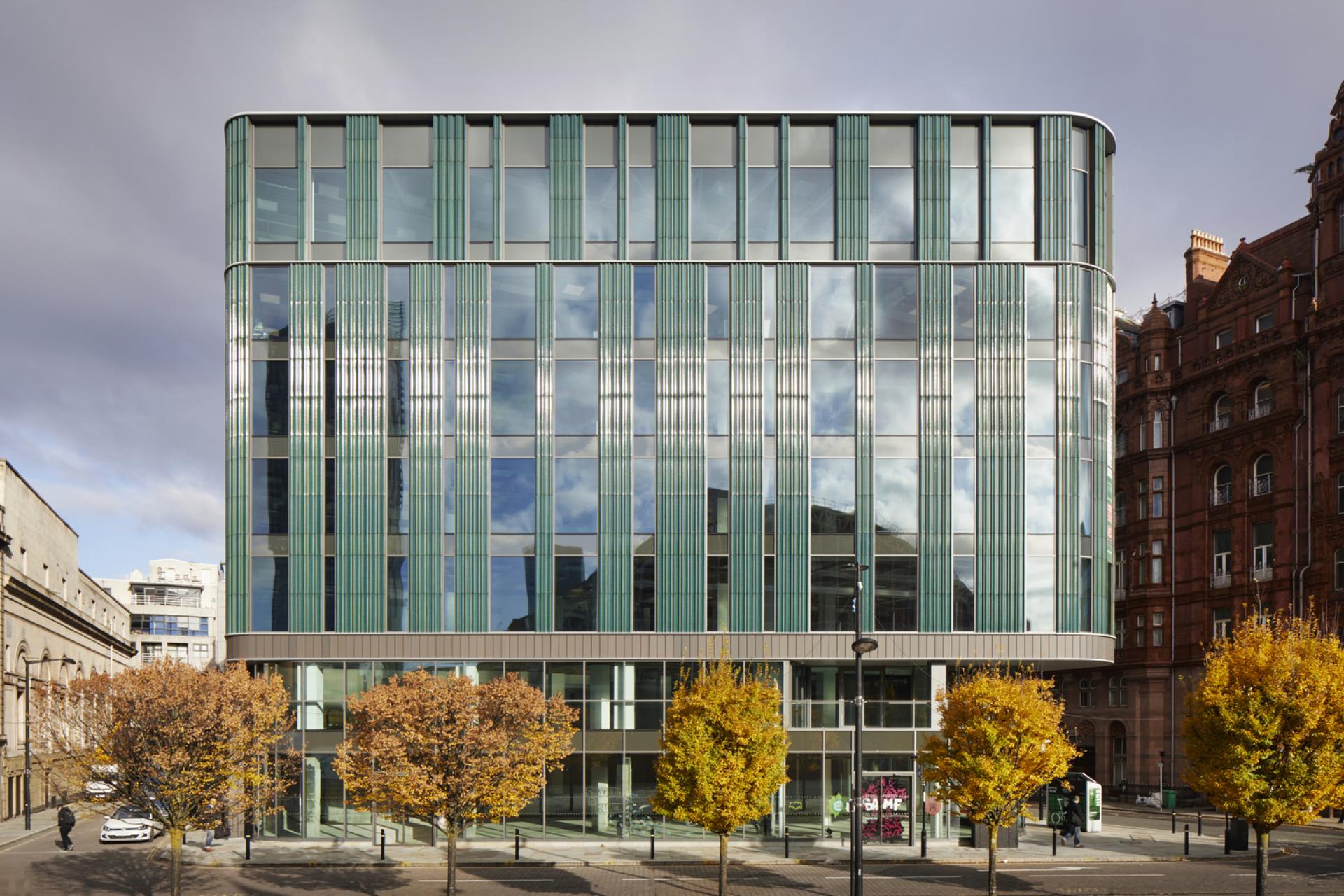 Modern glass office building showcasing innovative architecture, surrounded by autumn trees in an urban setting.