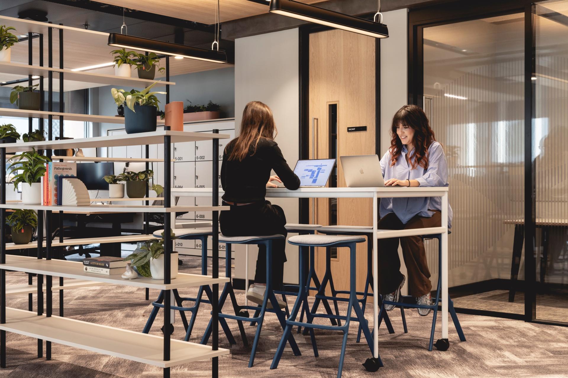 Stylish workspaces featuring Art Deco-inspired design with plants, a collaborative atmosphere, and professionals engaging with technology.