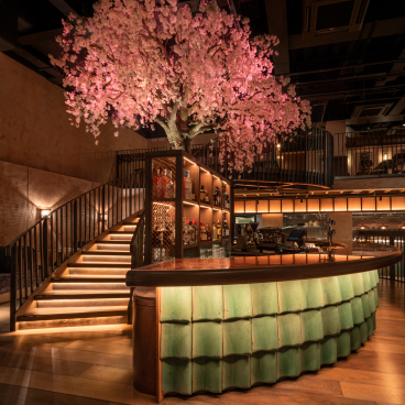 Elegant restaurant interior featuring a green bar design and a stunning cherry blossom tree, reflecting Chef Andrew Wong's new aesthetic.