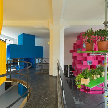 Colorful architectural installation by MVRDV featuring bright blue and pink structures, incorporating greenery and contemporary design elements.