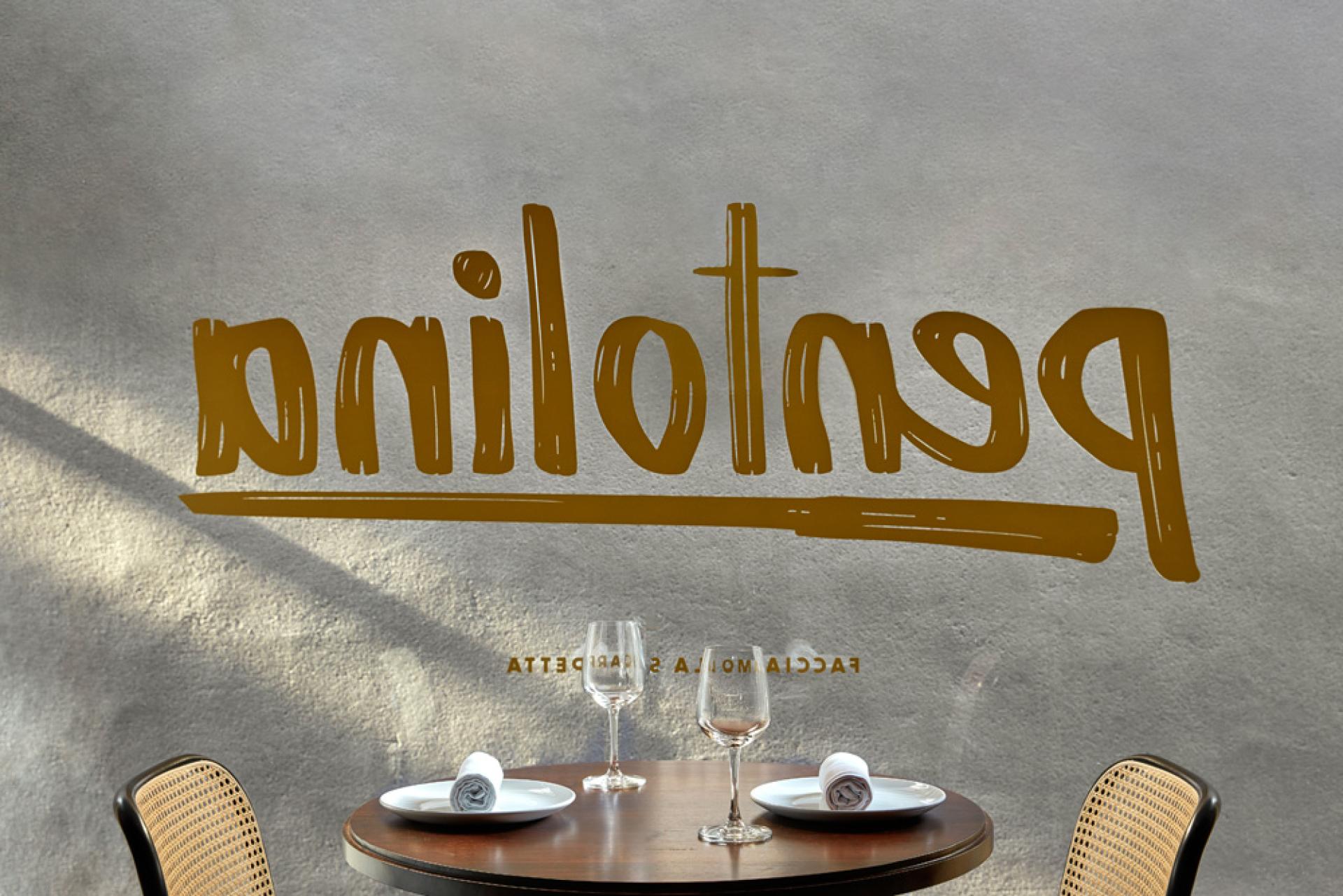 Pentolina restaurant's stylish interior featuring a wooden table set for dining with elegant glassware and decorative wall art.