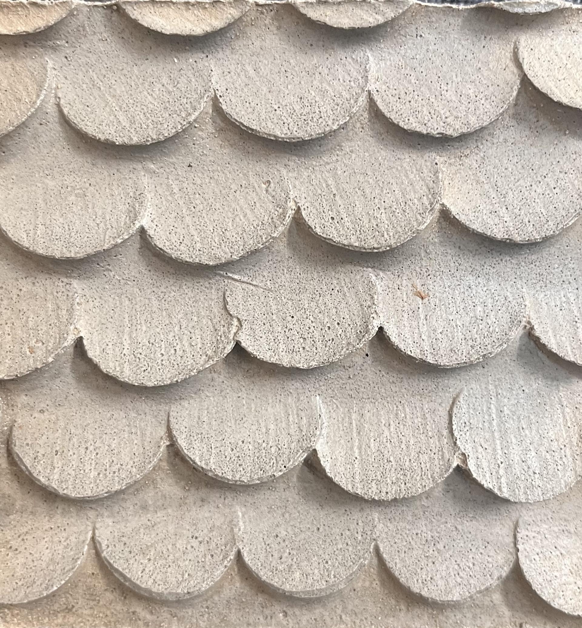 Textured surface of reimagined plastic waste, featuring scalloped shapes, showcasing creative reuse in collaboration with students.