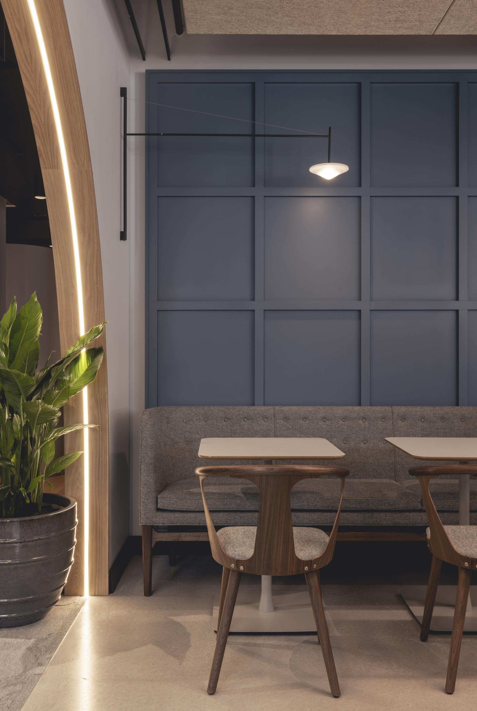 Modern workspace featuring a gray sofa, wooden tables, stylish lighting, and greenery, showcasing Ekho Studio's design for AstraZeneca UK.