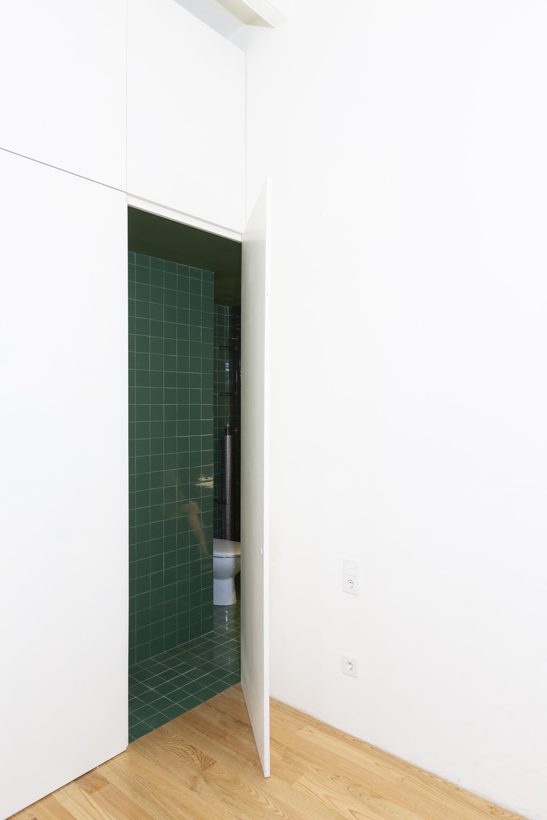 Modern bathroom entrance showcasing innovative green ceramic tiles and minimalist design elements in Spanish architecture.