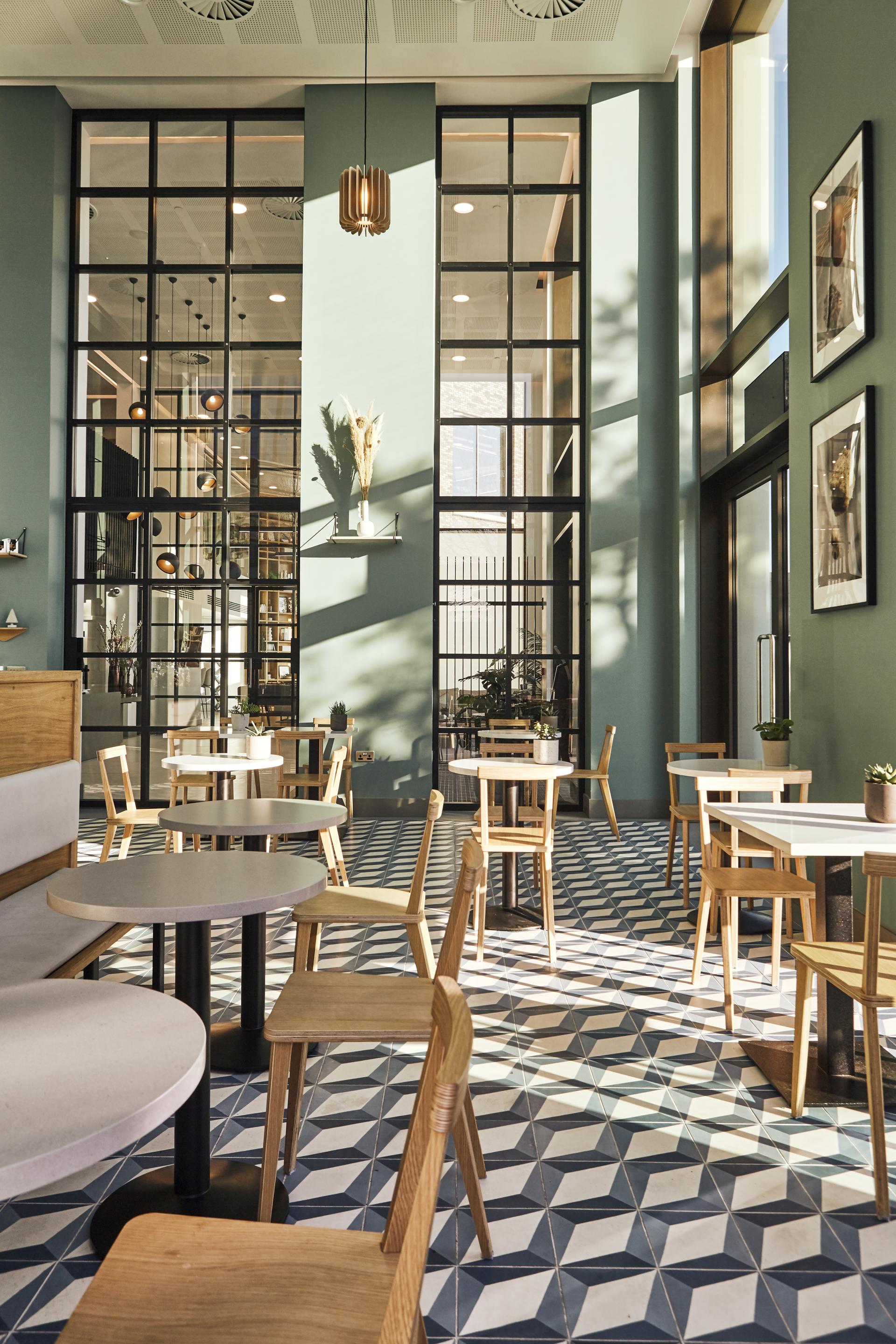 Modern cafe interior featuring Caesarstone quartz surfaces Raw Concrete and Misty Carrera, with geometric tiled flooring.