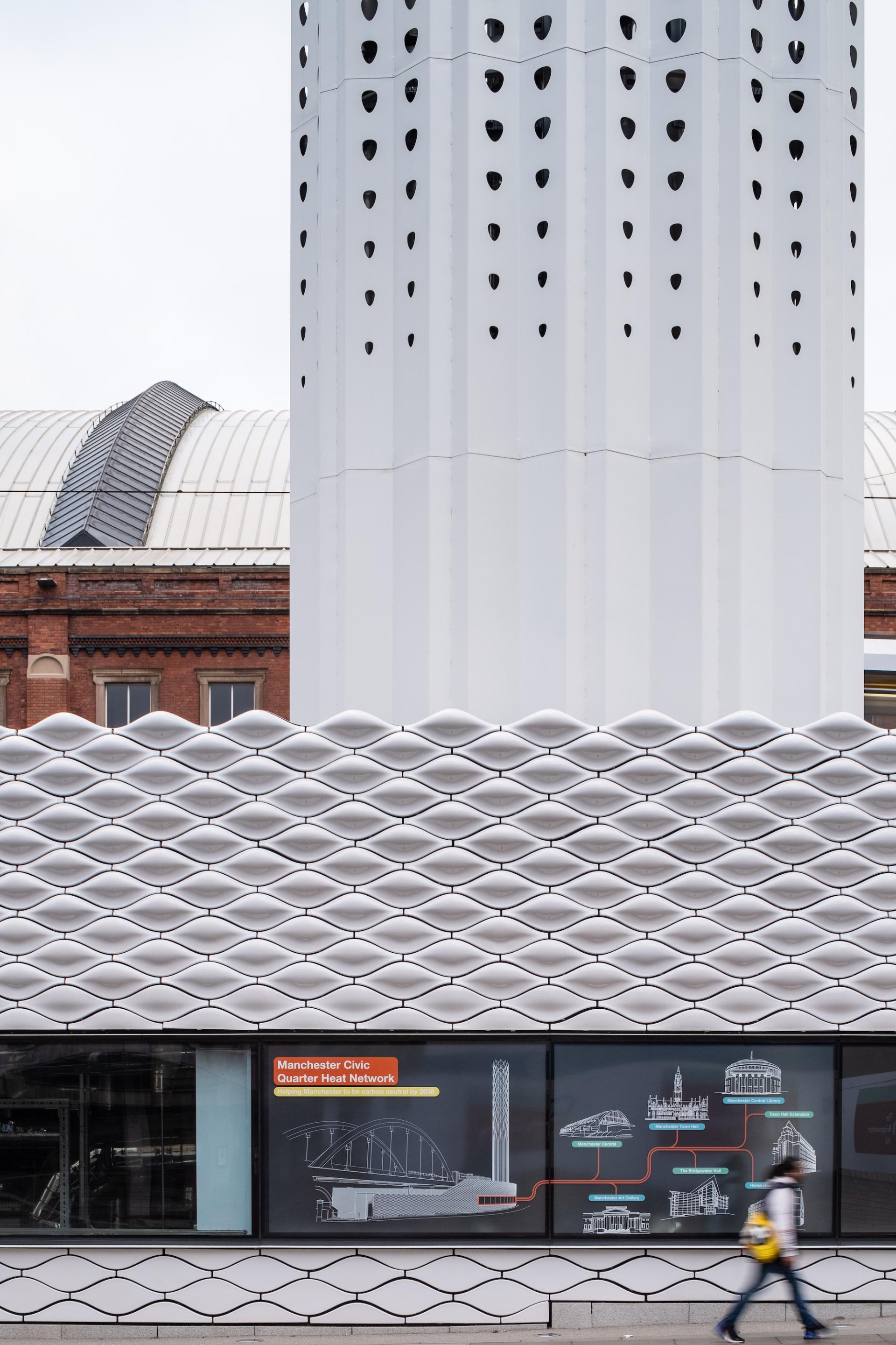 Modern white tower with patterned facade and information display about Manchester's civic quarter heat network.