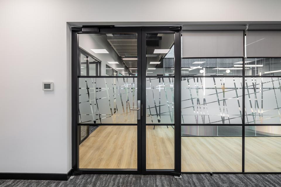 Modern glass doors open to a sleek workspace at The Bee House, enhancing collaboration in Milton Park, Oxfordshire.
