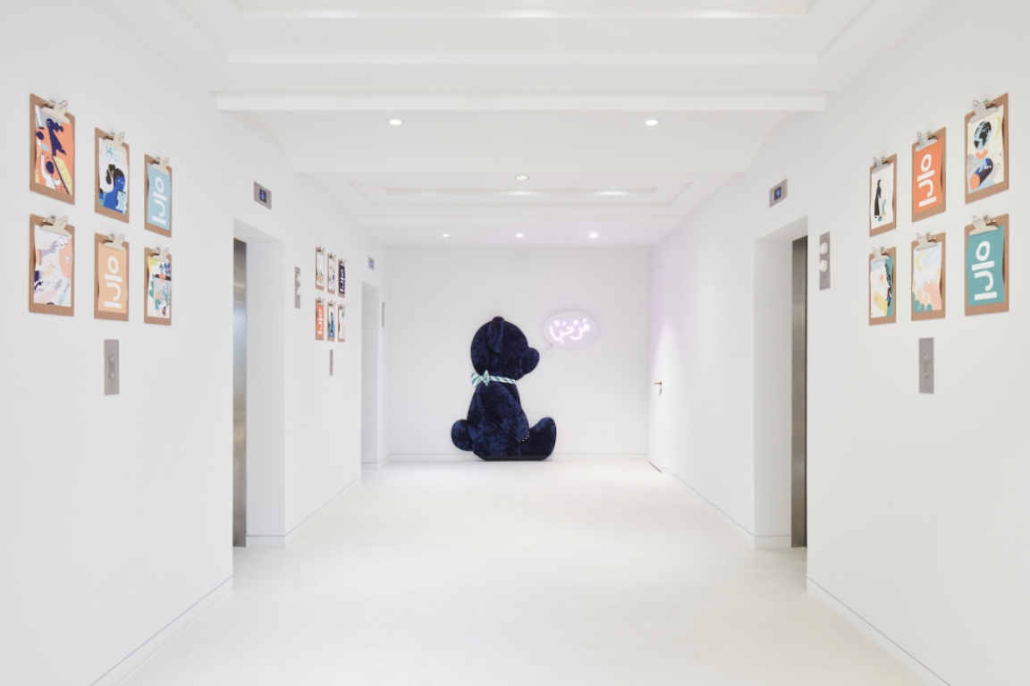 Vibrant hallway featuring colorful artwork, a plush teddy bear, and modern interior design elements by Roar studio.