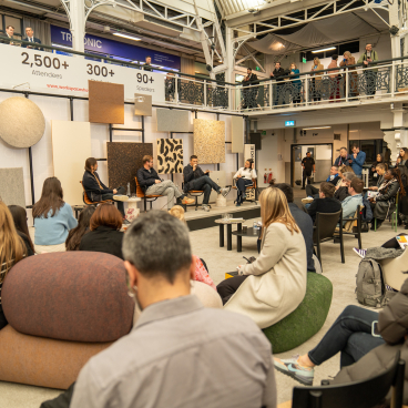 Attendees engaging in design discussions at the Workspace Design Show in Amsterdam, showcasing innovative workspace concepts and materials.