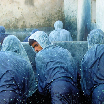 Artisans in blue garments work with indigo, showcasing the labor-intensive process of traditional dyeing techniques.