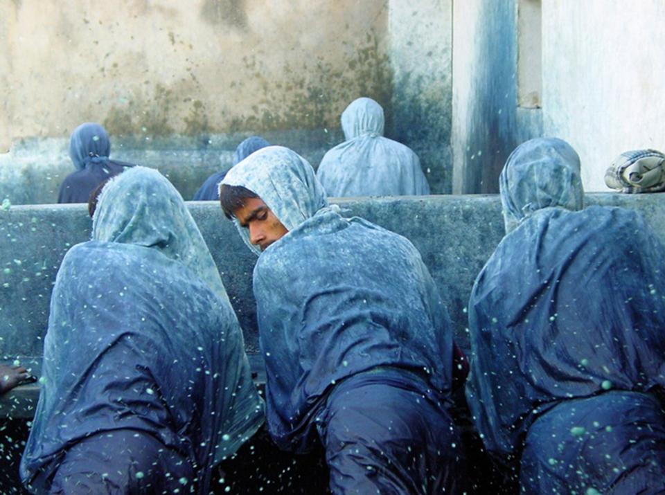 Artisans in blue garments work with indigo, showcasing the labor-intensive process of traditional dyeing techniques.