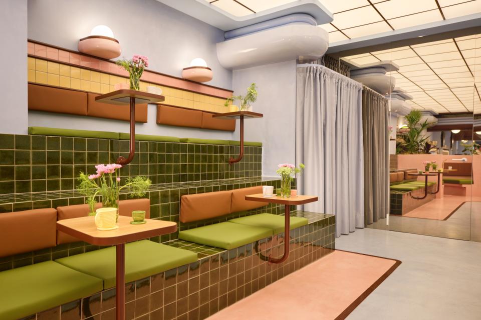 Colorful Art Deco-inspired seating area in a Barcelona ice cream parlour, featuring green tiles and floral arrangements.