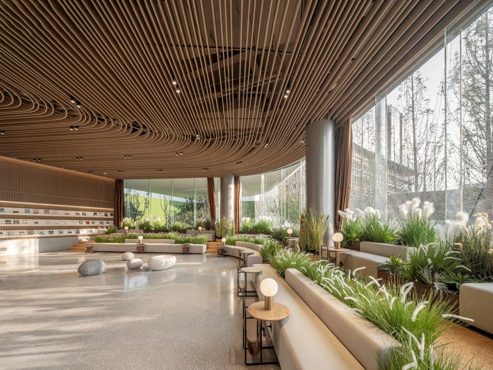 Lush greenery and sculptural wooden elements create a tranquil atmosphere in Karv One's Leas exhibition hall interior.
