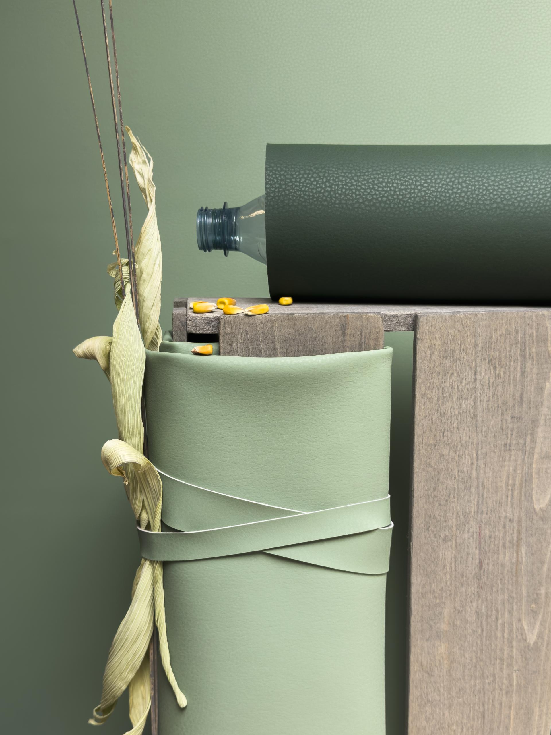 Volar Bio collection displays eco-friendly materials, featuring rolls of green fabric with a plastic bottle and natural elements.