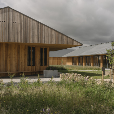 Sustainable farming education centre featuring modern wooden architecture amidst natural landscaping in the Cotswolds.