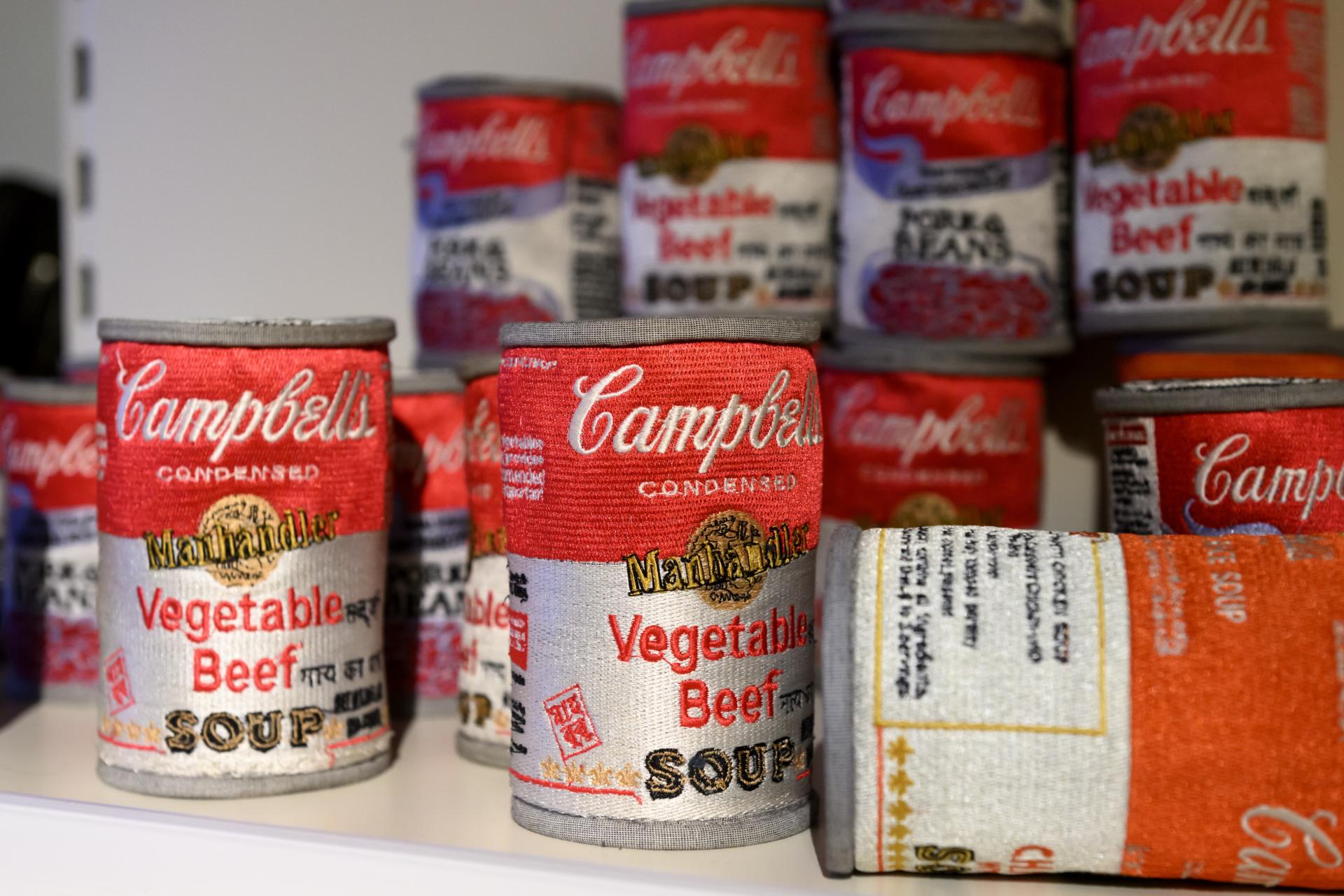 Colorful fabric replicas of Campbell's soup cans, showcasing the iconic designs, part of the Harewood Biennial 2024 exhibition.