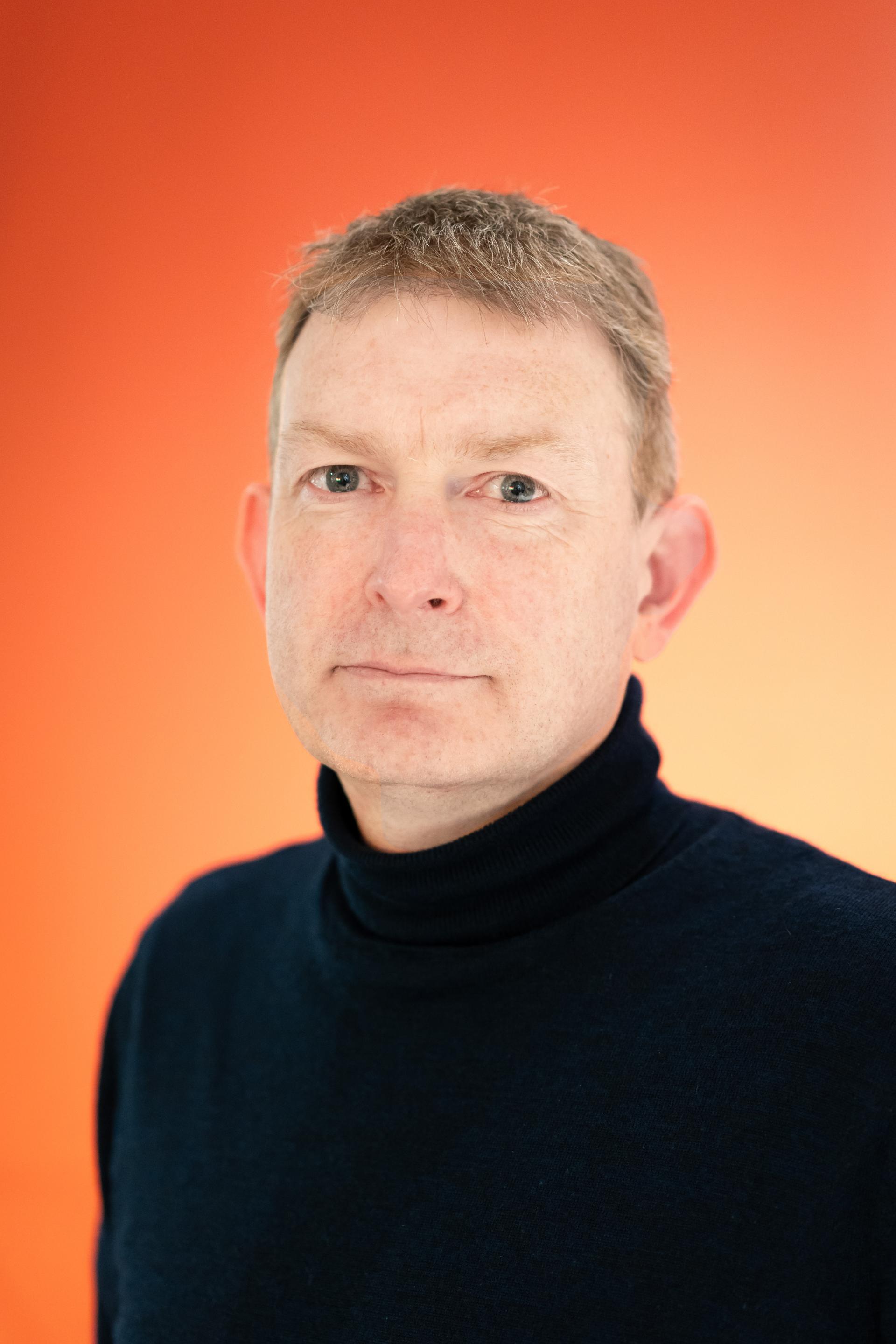 CEO of Yorkshire Housing, Nick Atkin, discusses workplace flexibility against a bright orange background.