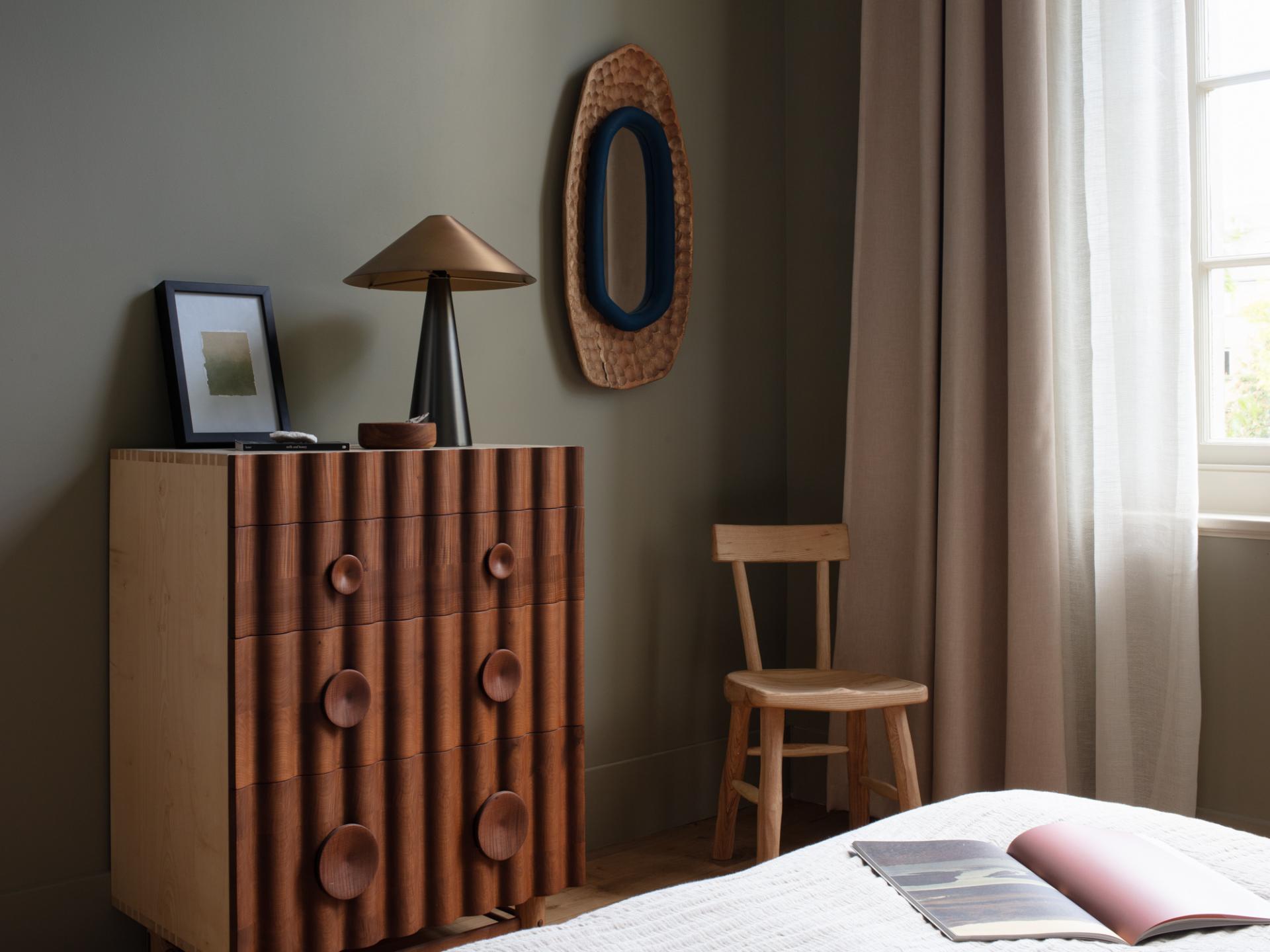 Stylish interior featuring handcrafted wooden dresser, lamp, and chair, showcasing Jan Hendzel's expressive furniture design.