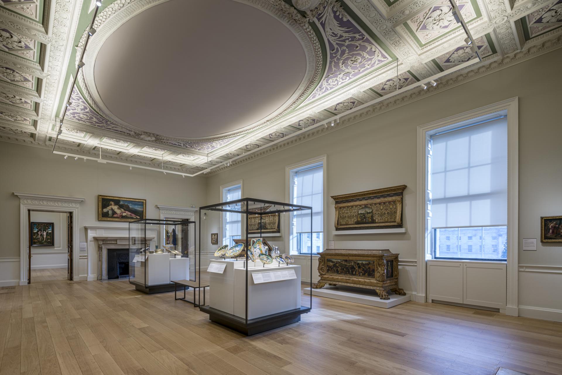 Brightly lit gallery at The Courtauld, showcasing historic artworks and decorative displays against an elegant ceiling.
