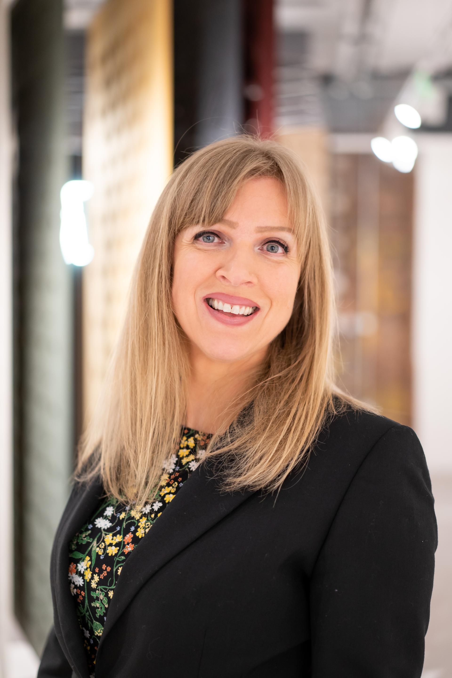 Professional woman smiling in a business setting, discussing sustainability topics at a recent seminar.