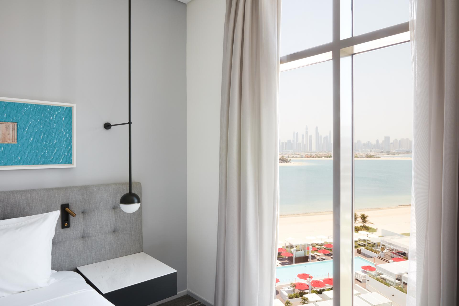 Modern hotel room in The8 Dubai, featuring sleek design, a panoramic view of the beach and city skyline.