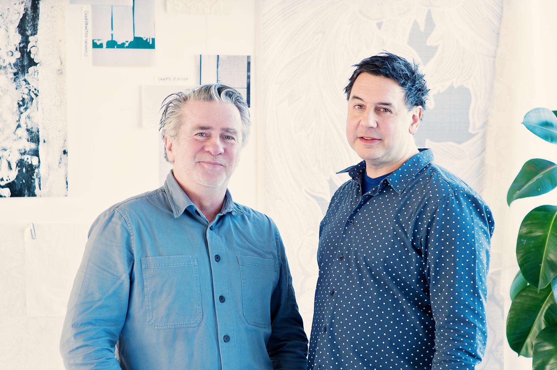 Two designers stand together in a creative studio, surrounded by exhibition design samples for Dundee Design Festival 2024.